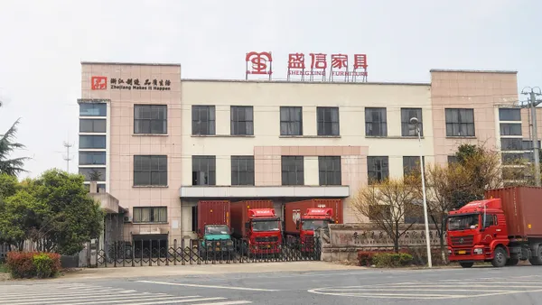 Shengxin (Shengxing Furniture) factory building in Anji with rooftop sign and container trucks at the gate